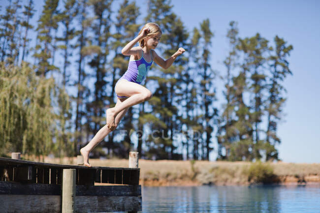 Menina pulando no lago a partir de molhe — Fotografia de Stock