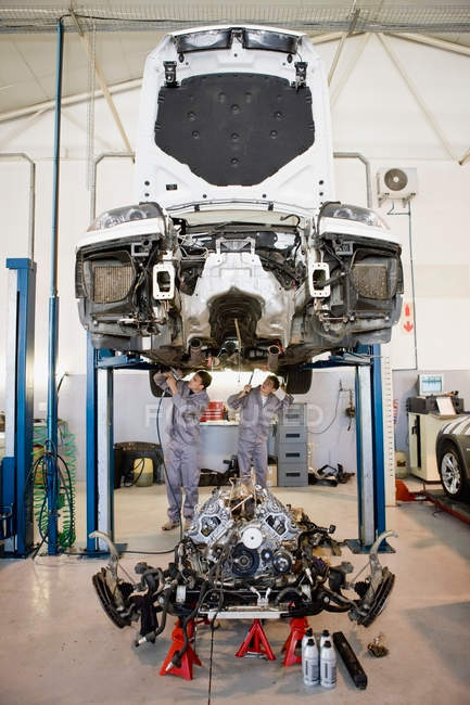 Механики, работающие на автомобиле в гараже — стоковое фото