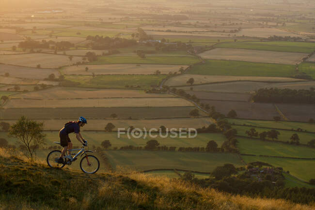 Motociclista de montaña bajando por una colina. - foto de stock