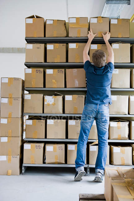 Homem arquivando caixas de papelão no armazenamento — Fotografia de Stock