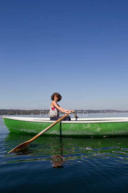 Жінка веслує на човні в нерухомому озері — стокове фото