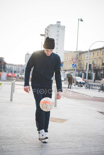 Giovane giocatore di calcio maschile giocare cucciolo Keepy sulla strada della città — Foto stock