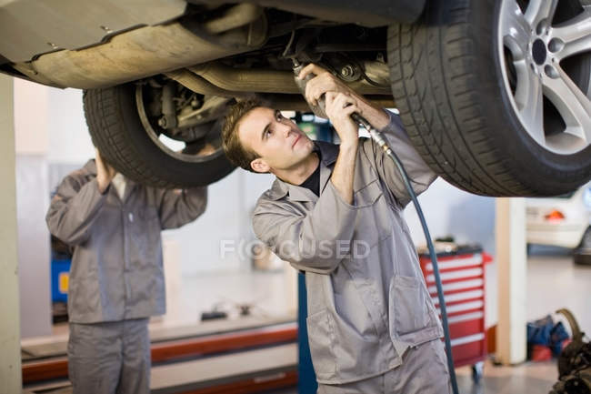 Mechanics working on car engine in garage — Stock Photo