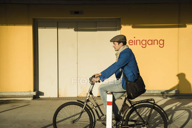 Young man cycling along urban street — Stock Photo