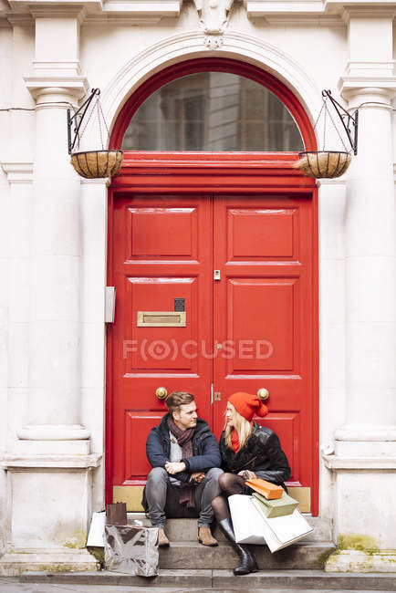 Junges Shopping-Paar, das vor der Haustür Pause macht, London, Großbritannien — Stockfoto