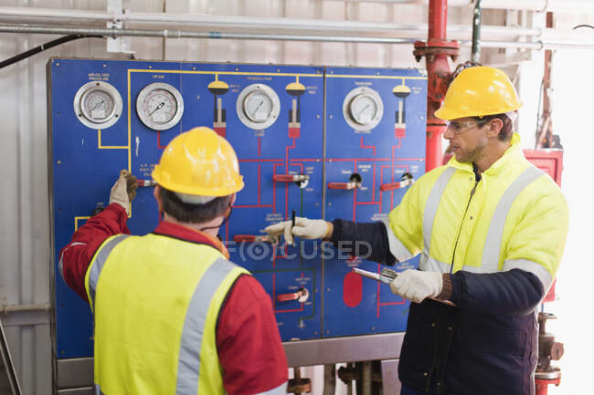 Рабочие проверяют манометры на нефтяной вышке — стоковое фото