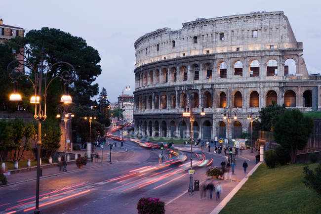 Observando vista del Coliseo roma con gente incidental caminando por las calles - foto de stock
