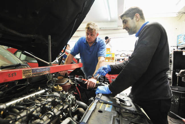 Meccanica maschile controllo motore auto in garage interno — Foto stock