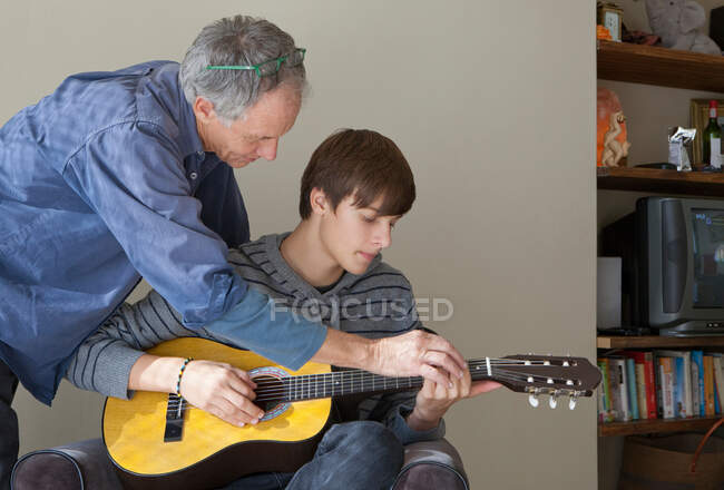 Батько, допомагаючи сина грати гітара — стокове фото