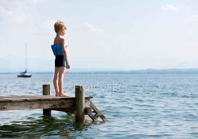 Junge steht mit Schwimmgürtel auf Seebrücke — Stockfoto