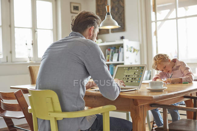 Padre ayudando a su hijo con la tarea en casa oficina - foto de stock