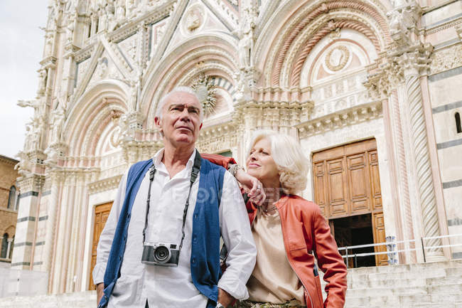 Pareja turística frente a la catedral de Siena, Toscana, Italia - foto de stock