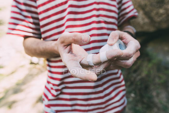 Средняя часть мужского валуна накладывает клейкую ленту на пальцы — стоковое фото