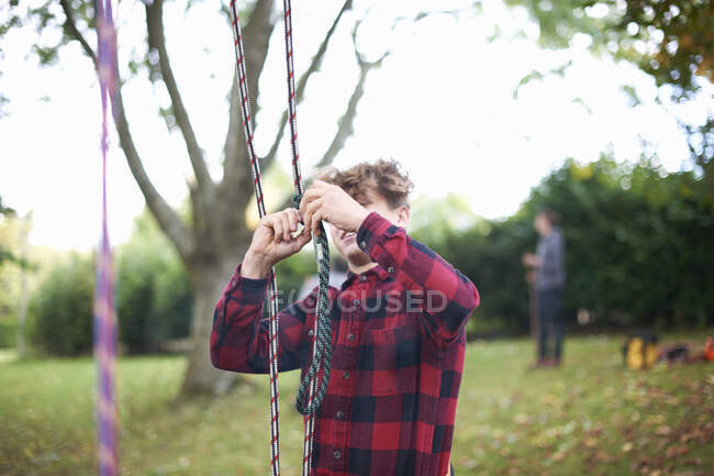 Trainee teenage male tree surgeon preparing climbing ropes — Stock Photo