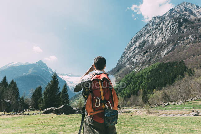 Rear view of male boulderer photographing mountains, Lombardy, Italy — Stock Photo