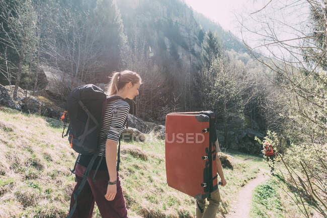Adult friends with bouldering mat backpack walking along rural path, Lombardy, Italy — Stock Photo