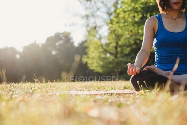 Femme mûre dans le parc, assise en position yoga, vue sur le bas angle — Photo de stock