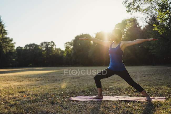 Femme mûre dans le parc, debout en position de yoga, les bras tendus — Photo de stock