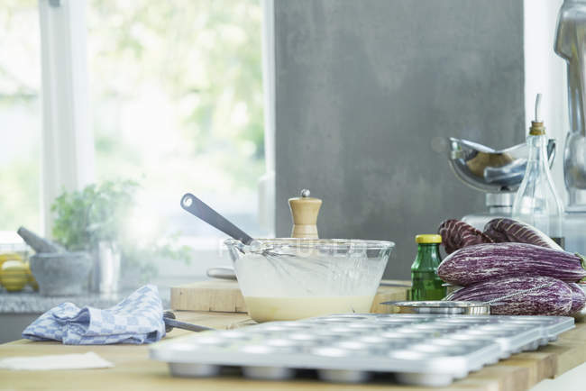 Tigela de mistura com batedor e assadeira na mesa na cozinha — Fotografia de Stock