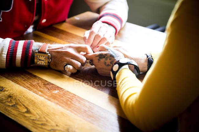 Paar hält Händchen auf Tisch — Stockfoto