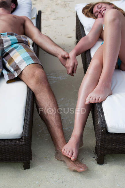 Пара розслабляється на ліжках на пляжі — стокове фото