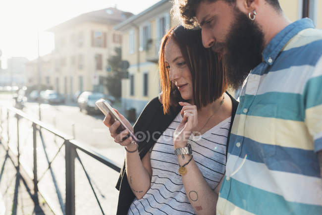 Paar auf Gehweg schaut aufs Smartphone — Stockfoto