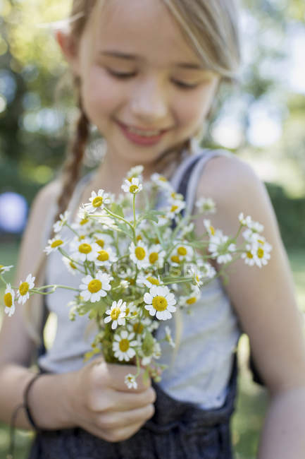 Girl pleased with bunch of camomile flowers — Stock Photo