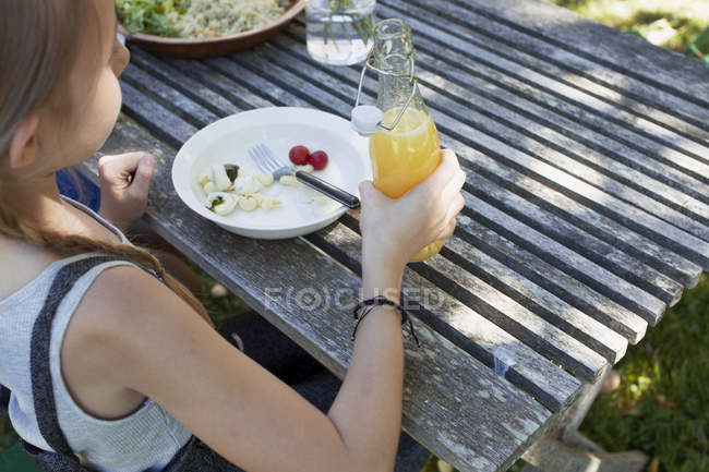 Chica almorzando en el jardín - foto de stock