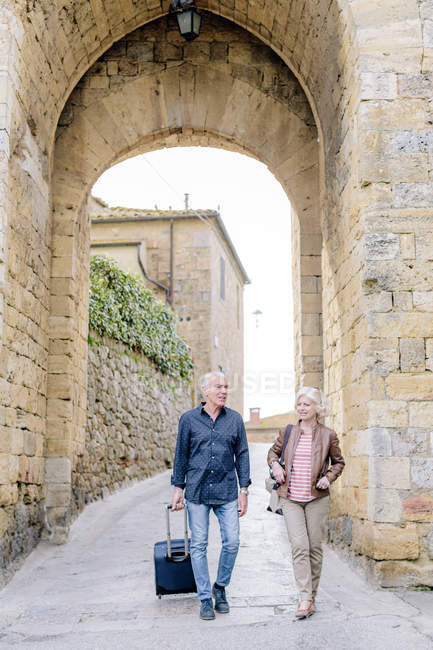 Coppia di turisti che camminano su strada acciottolata con valigia a ruote a Siena, Toscana, Italia — Foto stock