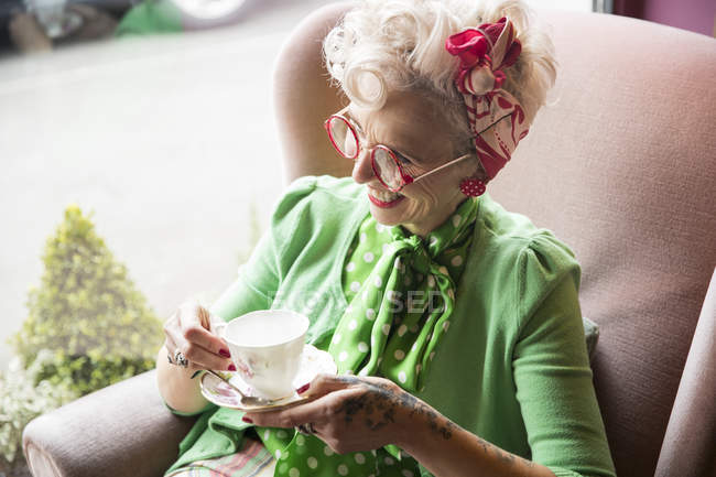 Vintage mature woman holding cup and saucer in tea room — Stock Photo