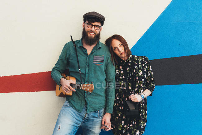 Portrait of cool couple leaning against abstract wall — Stock Photo