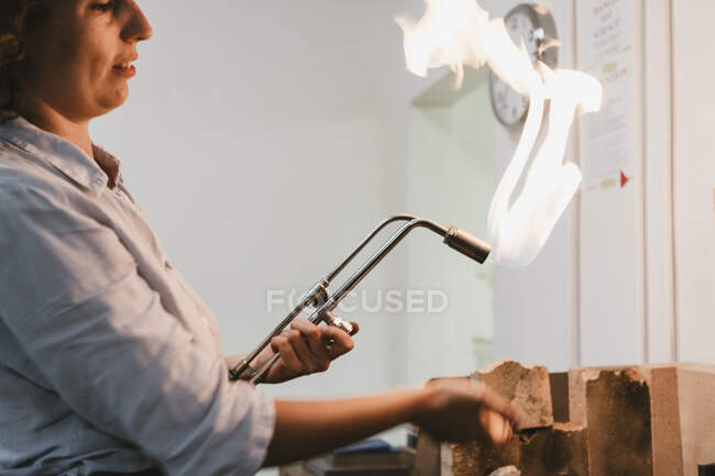 Female jeweller using flaming  blow torch at workbench — Stock Photo