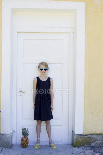 Menina em pé por abacaxi na frente da porta — Fotografia de Stock