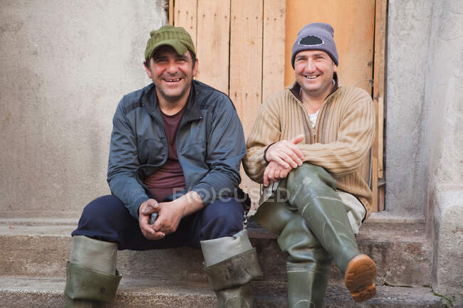 Два рибалки сидять на сходах, сміючись — стокове фото