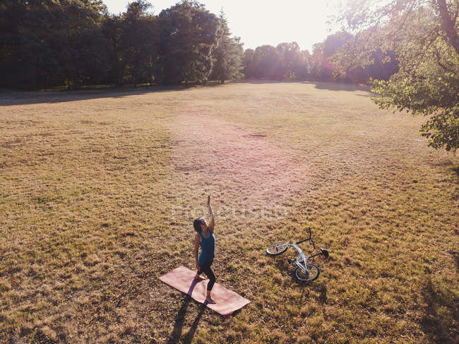 Femme mûre dans le parc, debout dans des positions de yoga, vue surélevée — Photo de stock