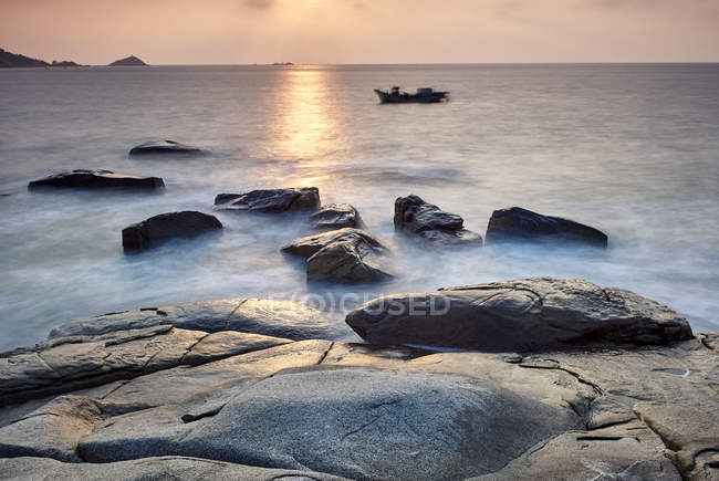 Rocas costeras y barco al amanecer, Dazuo, Fujian, China - foto de stock