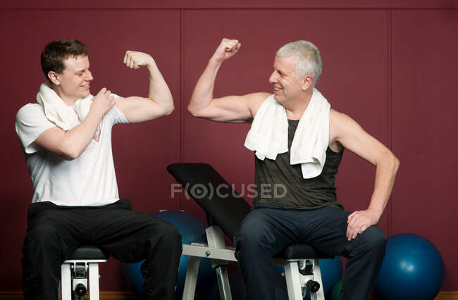 Pai e filho flexionando músculos no ginásio — Fotografia de Stock