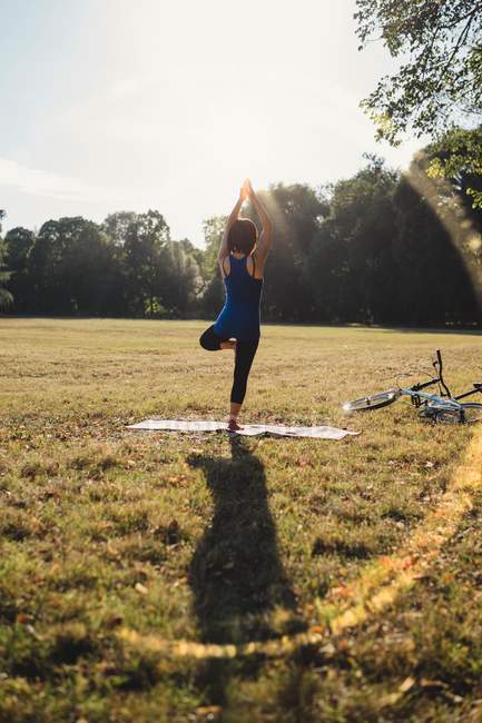 Donna matura nel parco, in piedi su una gamba, in posizione yoga, vista posteriore — Foto stock