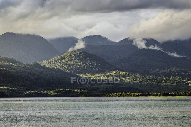 Brume montant des montagnes au-dessus du lac Vert, Parc national du Queulat, Chili — Photo de stock
