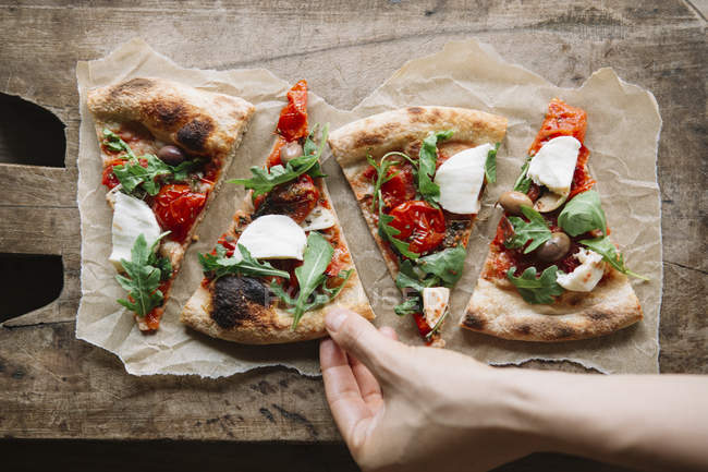 Cropped image of Woman taking pizza slice from chopping board — Stock Photo