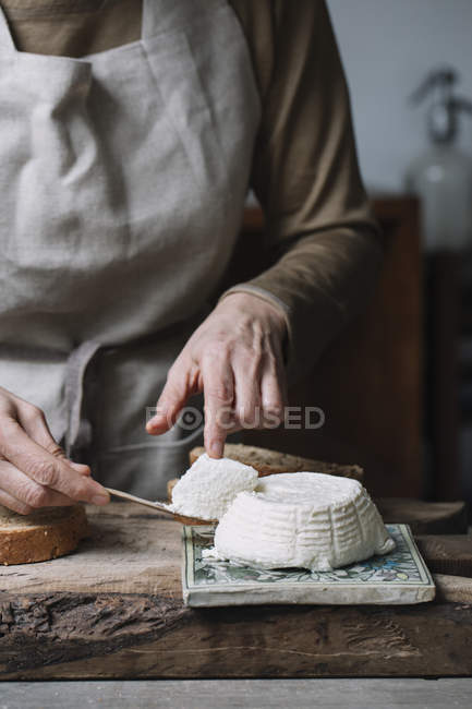 Woman taking slice from whole ricotta, mid section — Stock Photo