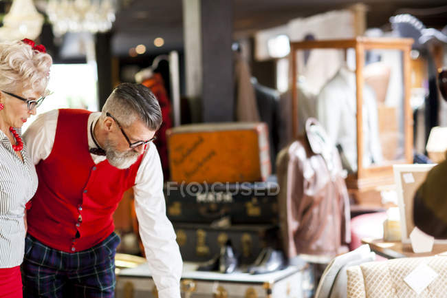 Quirky vintage couple looking down in antiques and vintage emporium — Stock Photo