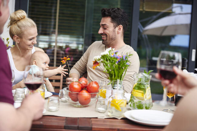 Couple with baby daughter at family lunch on patio table — Stock Photo