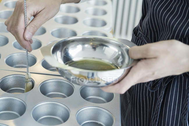 Chef brushing oil onto metal baking tray — Stock Photo