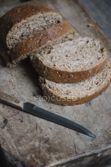 Pão fatiado em tábua de cortar com faca, close-up — Fotografia de Stock
