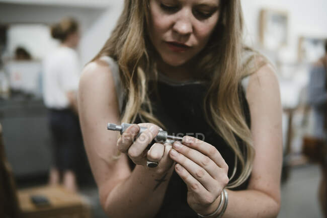 Female jeweller using hand tool in jewellery workshop — Stock Photo