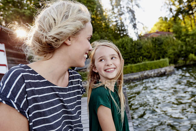 Mother and daughter enjoying themselves by water — Stock Photo