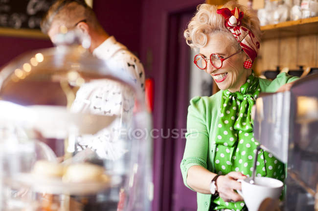 Quirky vintage woman using coffee machine in tea room — Stock Photo