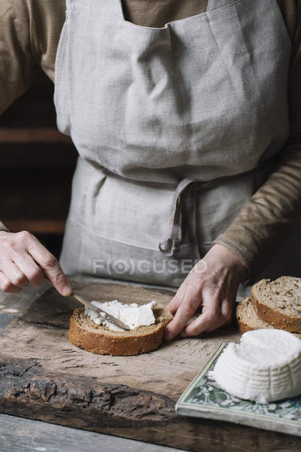 Mulher espalhando queijo ricota em fatia de pão, seção meio — Fotografia de Stock