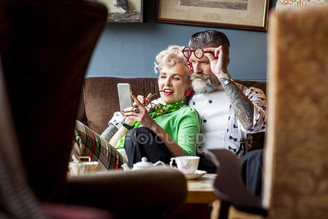 Schrulliges Oldtimer-Paar schaut in Teestube aufs Smartphone — Stockfoto